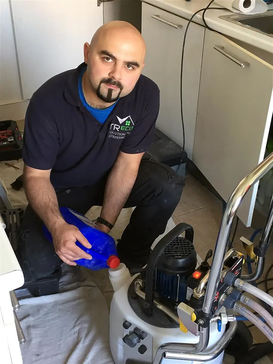 Tomasz Rusin, owner of Tr-Eco Solutions, performing power flushing in a kitchen setting.
